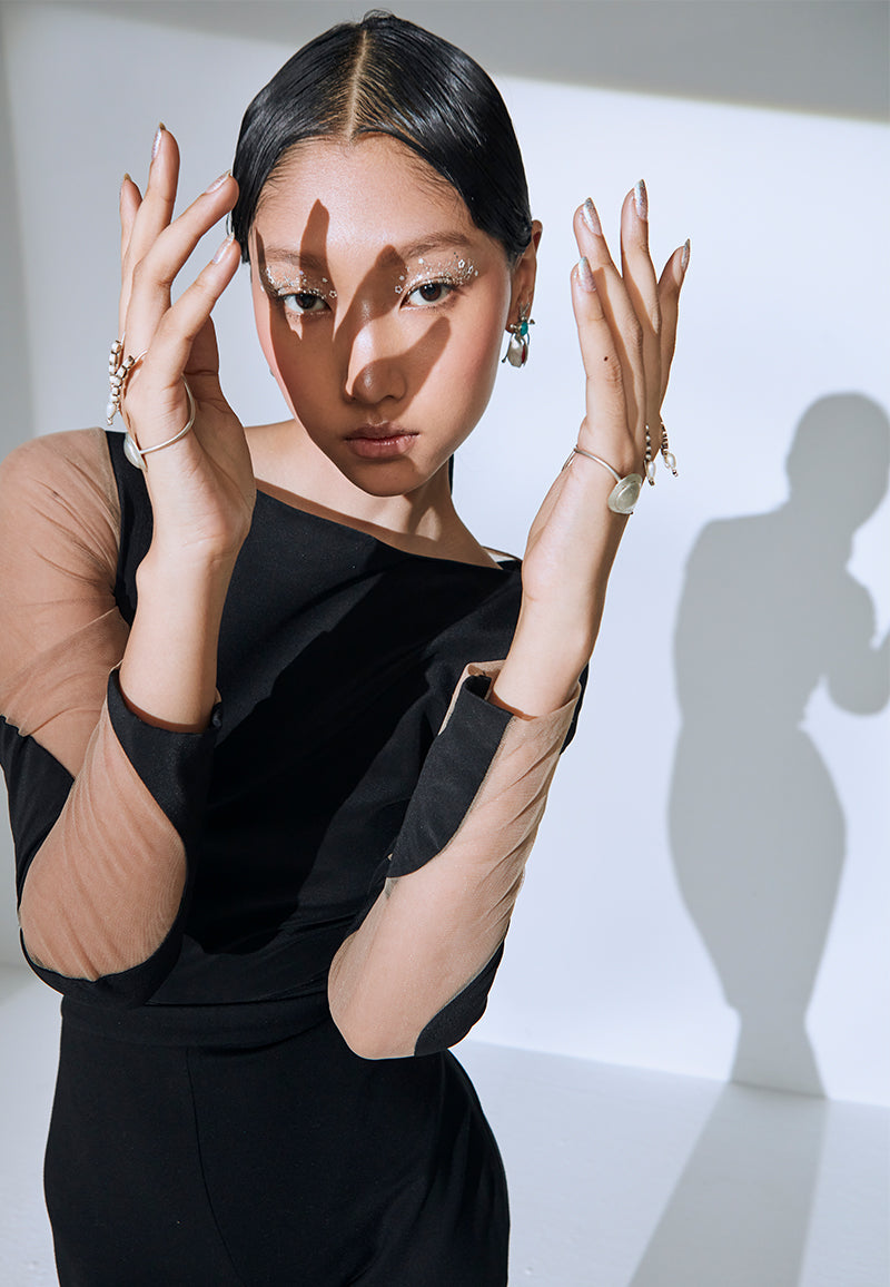 Tailored in crepe and net, this bodysuit gives some classic 80s fashion vibe. The long sleeved bodysuit features a wavy boat neckline and strips of curvy patchwork going from the sleeve to the back. It has a zip closure on the side seam. Wear it with a pair of shorts or flared pants/jeans along with sneakers or heels to complete the look.