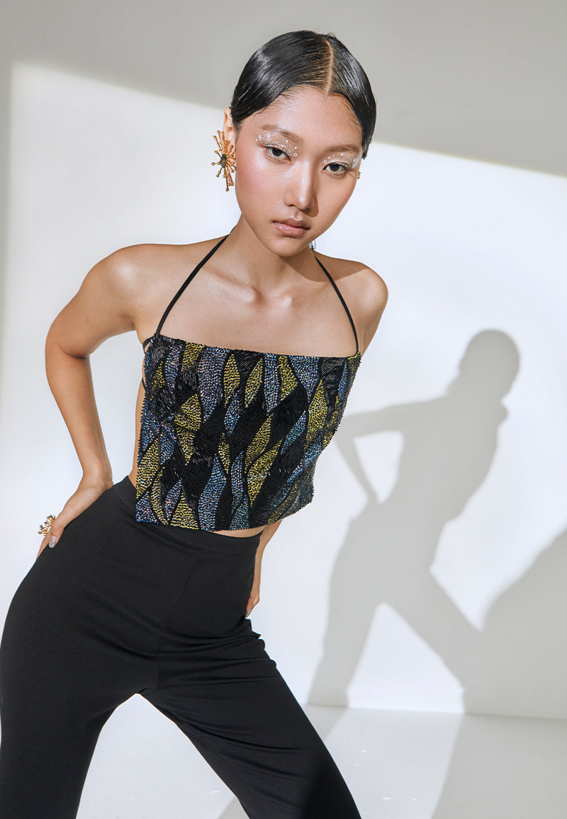 Hand-embroidered with yellow, blue, and black sequins this backless halter-neck square cropped top features tie-up details around the neck and the bust. Pair this flared pants or a mini skirt and heeled sandals to complete the look.