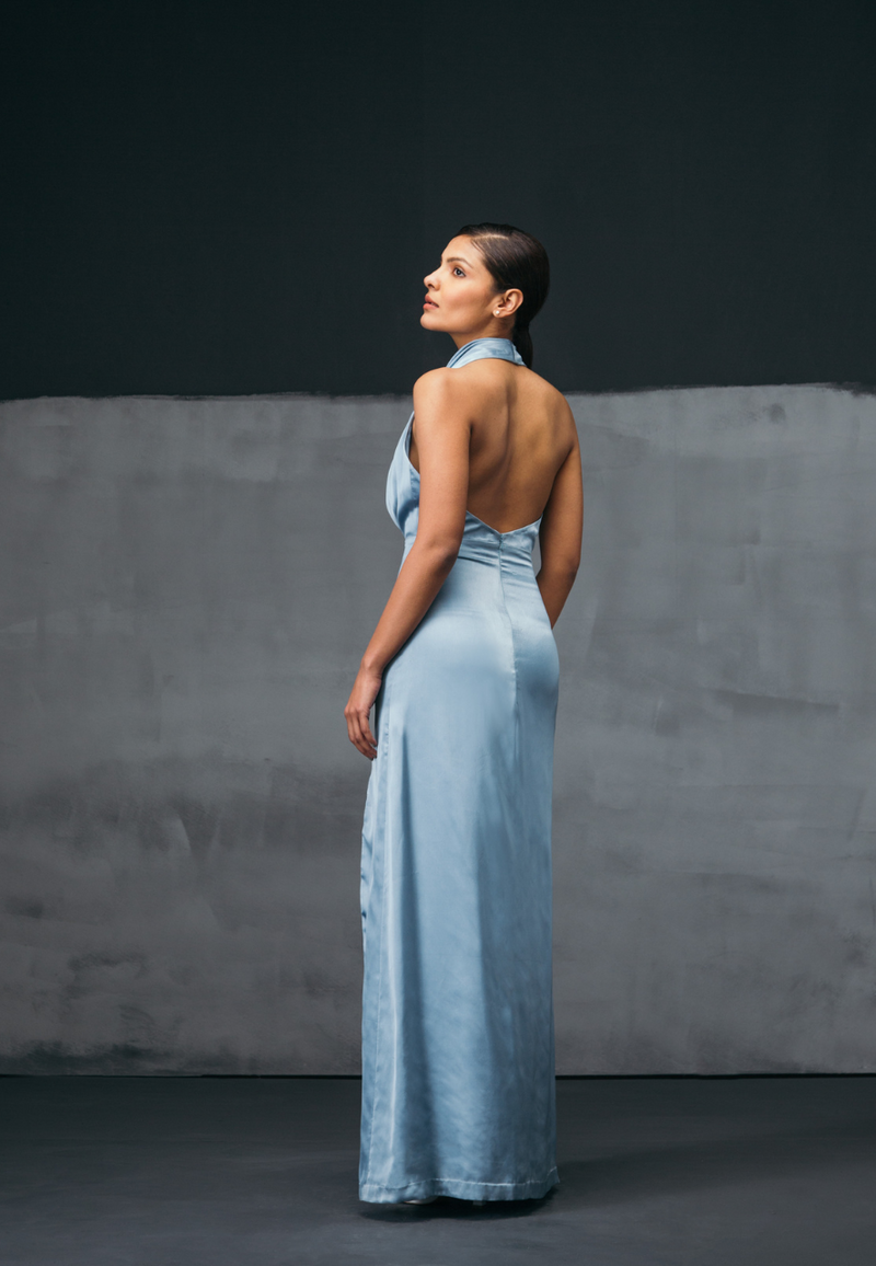 Mannat Gupta’s mini and maxi dresses collection. Shine like a star with our icy blue maxi dress. This turquoise color will add more value to your party look. Made with glossy silk satin with an alluring cowl neckline and an undulating high-slit cut that tumbles gracefully to a floor-pooling hem.This dress heightens the modern elegance of maxi dress. You can wear this maxi dress at a glamorous dinner or for a cocktail party. Pair with high heels or sandals and some diamonds to complete the look.