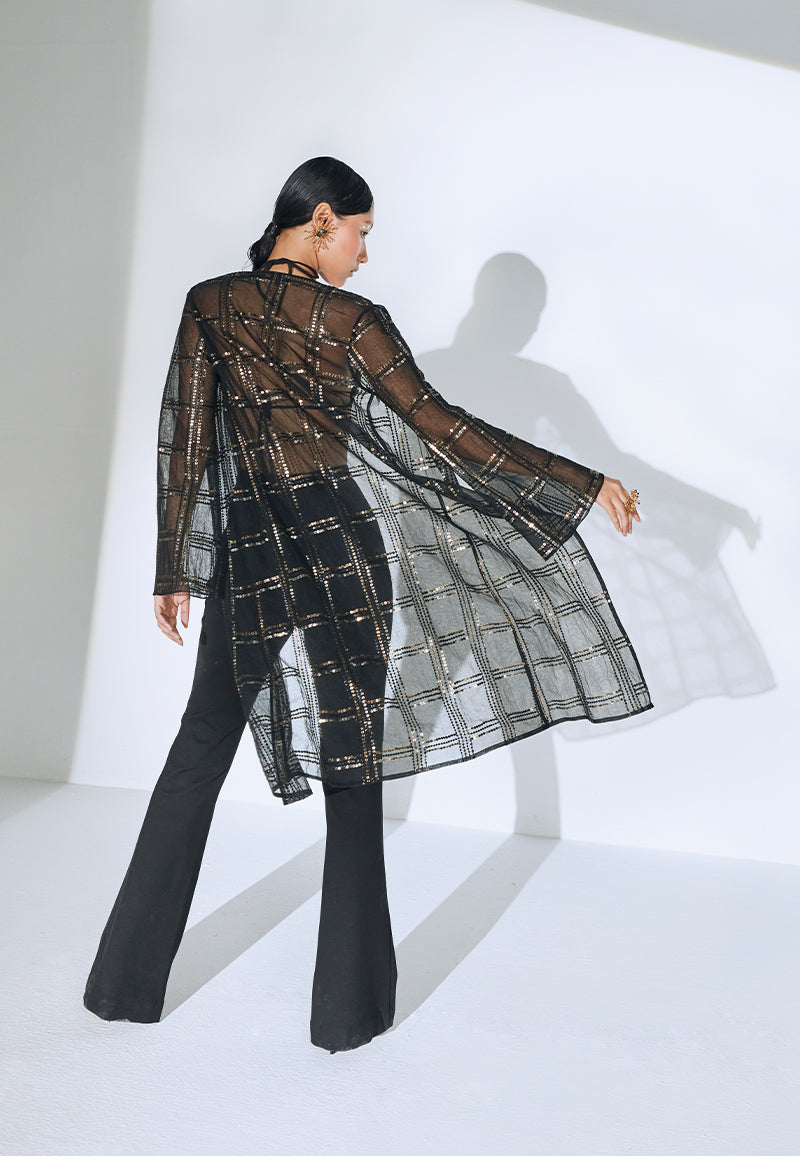 Good for a breezy summer evening or a dinner, this hand-embroidered loose-fit black net jacket is one timeless piece that you can pair with almost anyything. This knee-length jacket features long, flared sleeves and checkered embroidery with rustic gold and black sequins in different sizes. Wear it over a dress or a co-ord set for dinner or even over a swimsuit at the beach or a beach party.