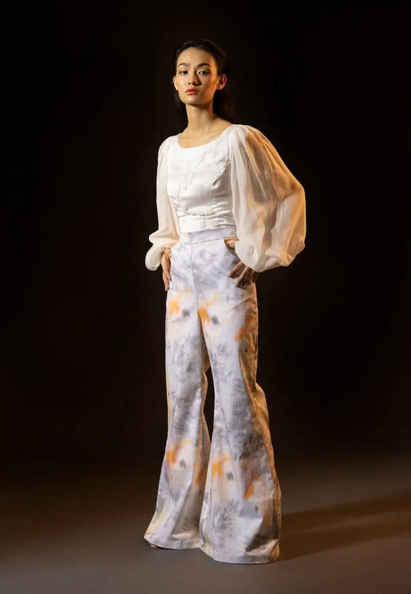 Mannat Gupta's collection of tops for women. This white bodycon top is made using silk and chiffon. The top features a round neck and leaves embroidery on the front with white beads. The long puffed sleeves of the top are made using chiffon to add volume. This versatile, comfortable and minimal blouse can be worn with anything: pants, jeans, skirts, shorts, etc. It is perfect for an elegant date night.