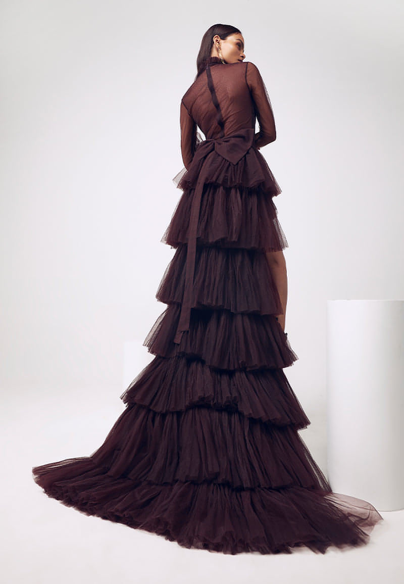This detachable wine ruffled gown is modernized through an intriguing juxtaposition of layers and transparencies that gives it an ethereal feel. This expertly crafted ensemble with a special layered ruched detachable trail, ruched bodysuit and gathered mini skirt is versatile. The bodysuit can be worn separately with a pair of jeans or pants and the mini skirt can be paired with a corset, bustier or a bodycon top.