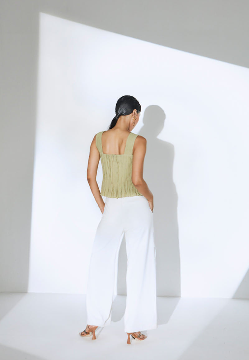 Doll-up in this ruched, sleeveless top in pastel olive green. This lightweight georgette bodycon top is peplum-inspired and features a sweetheart neckline. The top has a zip closure at the center back. Pair it with a skirt, jeans or pants with sneakers or heeled sandals for a day out in the city.