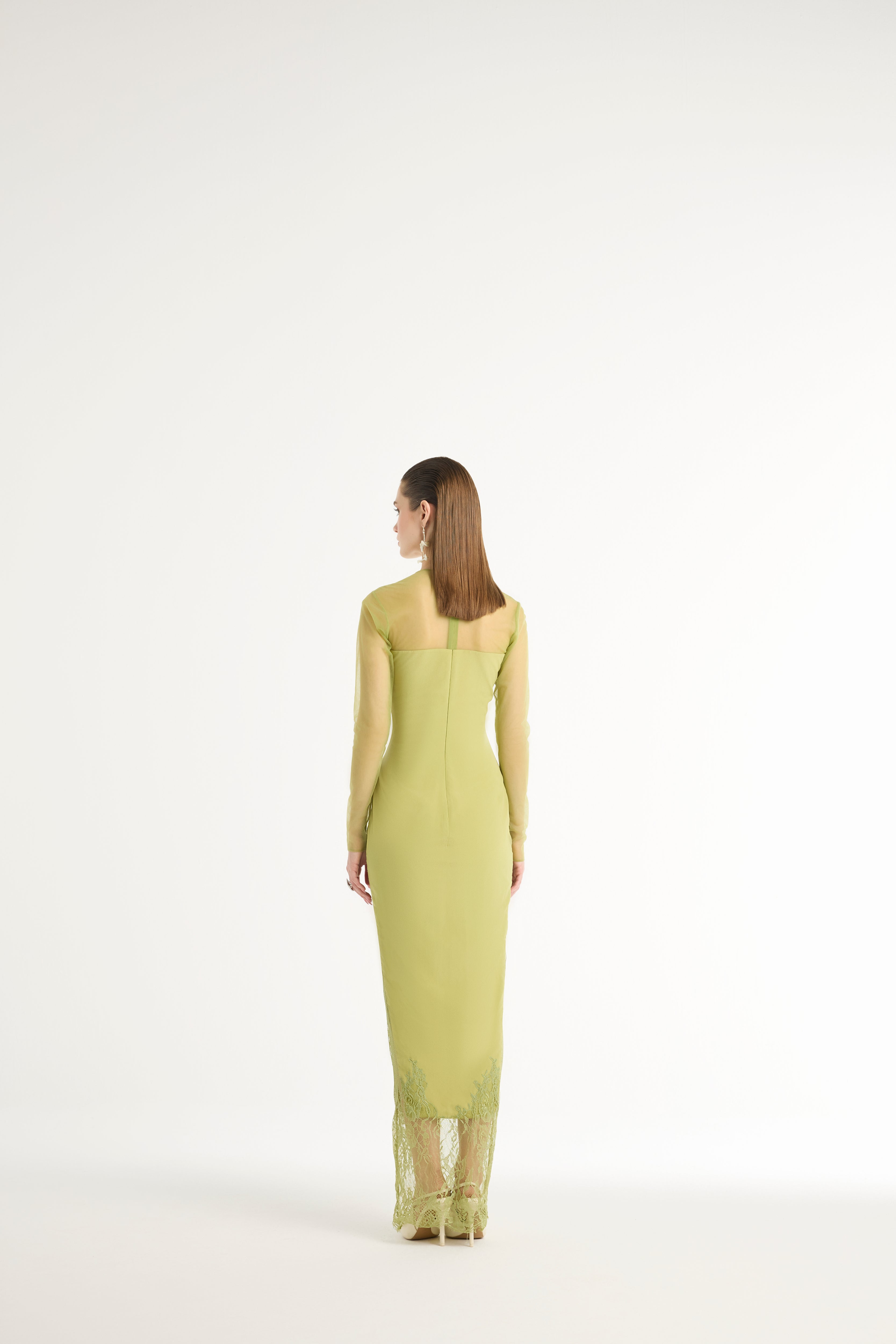 Woman wearing a light green dress with lace details on a white background