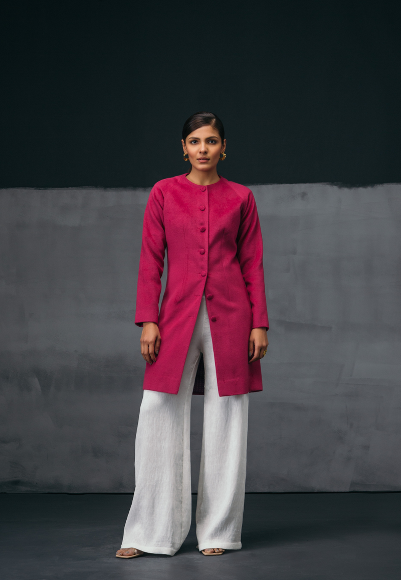 Mannat Gupta's collection of women's jackets and coats. This collarless pink wool coat features wool buttons as closures on the front. It has long sleeves and is cut right on the knee. It the perfect coat for breezy winters. You can wear it to work or for your next dinner plan with girlfriends. Pair it with straight pants and a cropped sweater along with pumps to complete the look. 