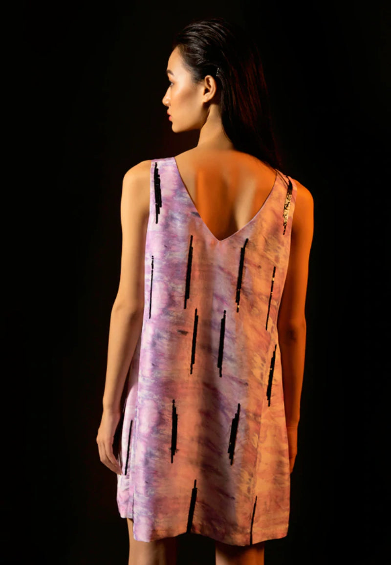 Versatile and minimal dress collection from Mannat Gupta which every woman will love to have. You can style in this beautiful embellished short A-line dress which is made of luxe silk and printed with a purple tie-dye pattern. This flared mini dress is crafted with black sequins. Pair this sleeveless mini dress with heeled sandals and minimal jewelry for your next night out.