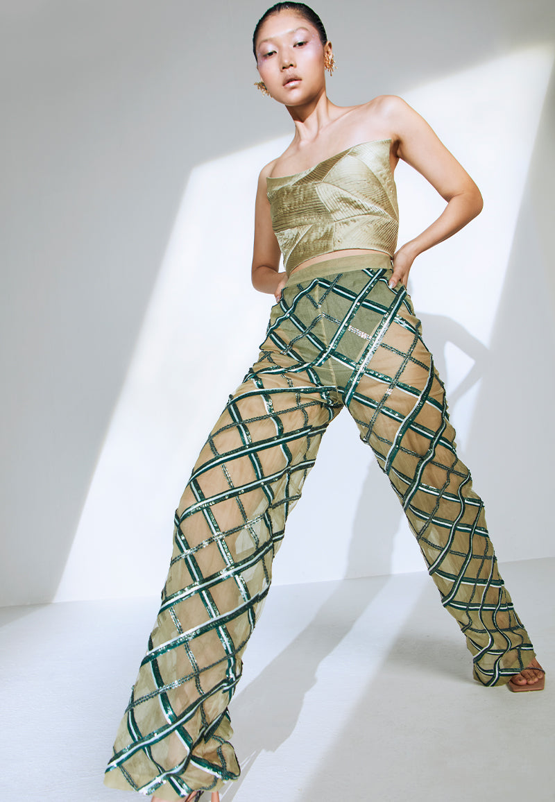 Hand-embroidered on pastel olive green net, the sheer pant features criss-cross embroidery pattern playing with different sequin sizes and colors in green. This transparent pant fall straight to floor from the high-waist. It has a zip closure at center back and comes with a pair of green underpants. Wear it for a fancy dinner party with heeled sandals or pumps and a bustier or corset to complete the look.