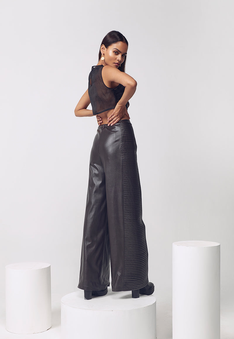 This caramel brown flared leather pants with horizontal pleat detail on the side seams give structure and adds volume to these comfortable pants. This pant is crafted in artificial leather and sits high on waits and falls to the floor. Pair it with a crop top, bustier or corset in the summers or a sweater in the winters for versatile, minimal looks.